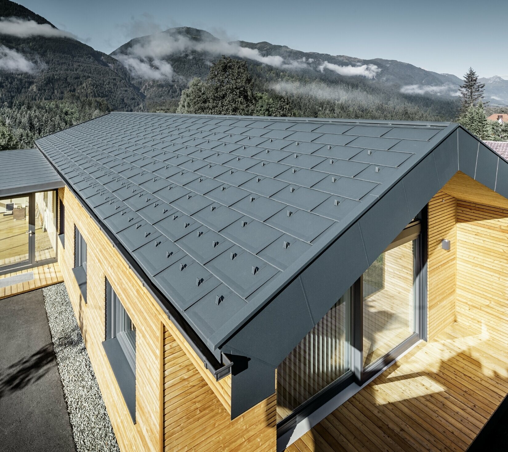 Nuovo edificio per uffici di Holzbau Faltheiner con facciata in legno di larice, ampie finestre e tetto PREFA color antracite.