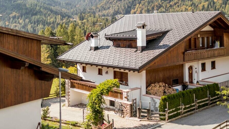 Casa tradizionale con copertura del tetto PREFA testa di moro e facciata con elementi in legno e intonaco