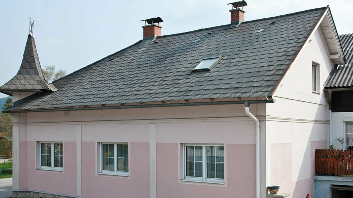 Casa prima della ristrutturazione del tetto con tegole PREFA in Austria - prima la copertura era in fibrocemento Eternit, facciata rosa