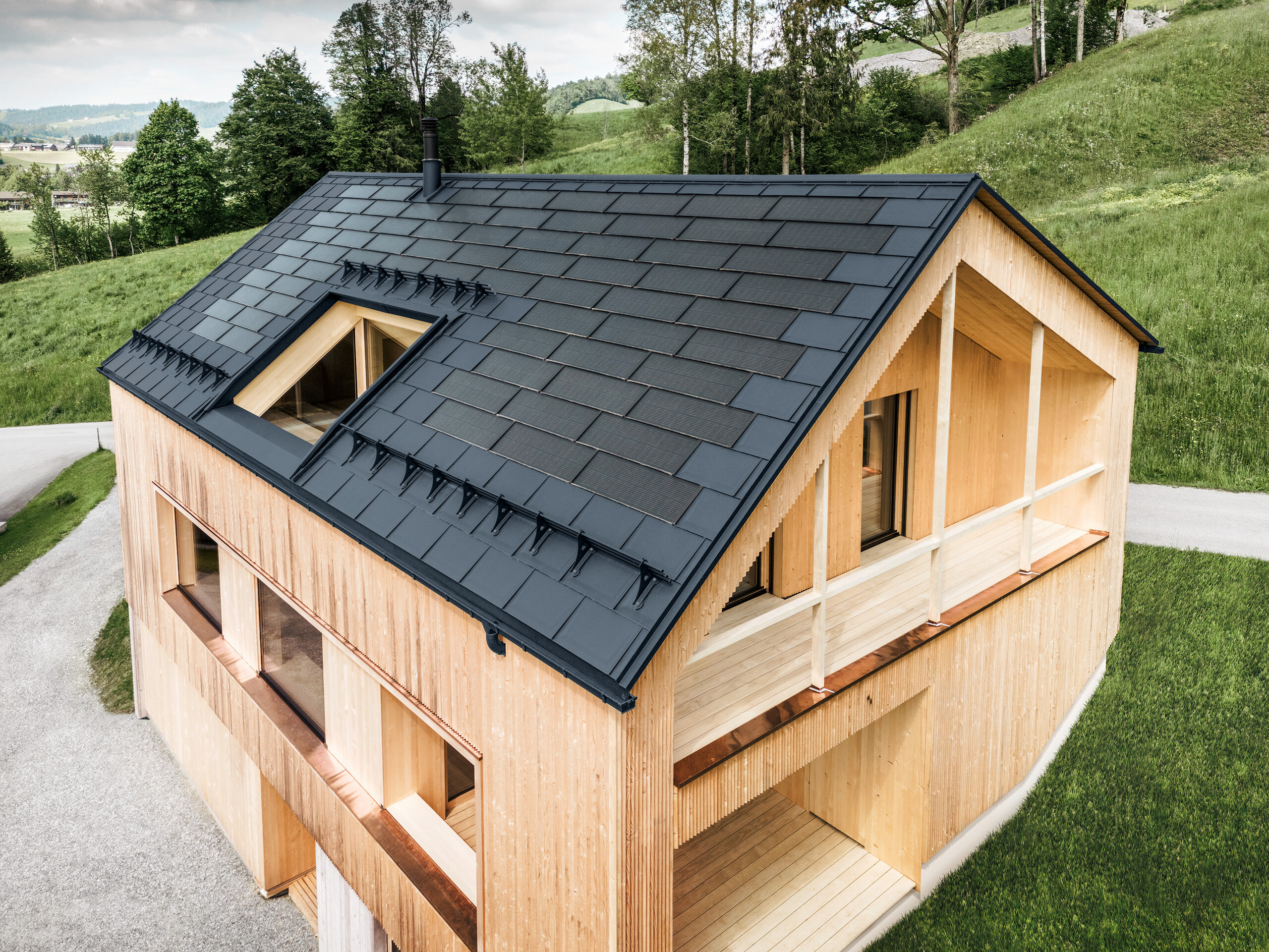 Casa indipendente nel villaggio austriaco di Egg con il pannello solare PREFA e il pannello R.16 in antracite, abbinato a una facciata in legno