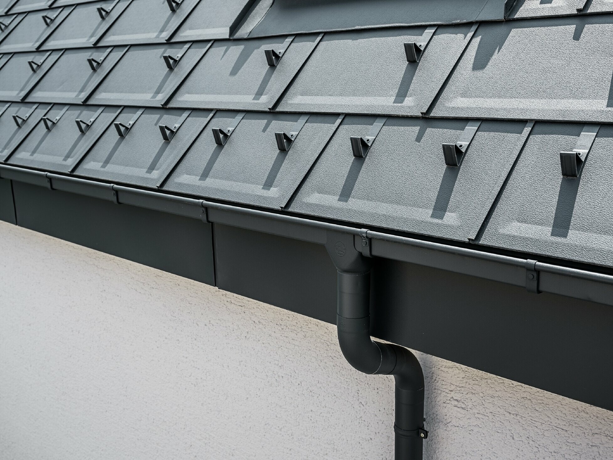 La superficie del tetto ripida è rivestita con il pannello R.16 con canale quadro PREFA con bocchetta e tubo pluviale in antracite.