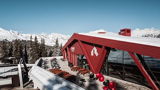 Rifugio e ristorante Summit Mountain Club ricoperto di neve in un paesaggio dell'area sciistica Racines Giovo stupenda con foto dettaglio della facciata in scandole PREFA P.10 rosso ossido.