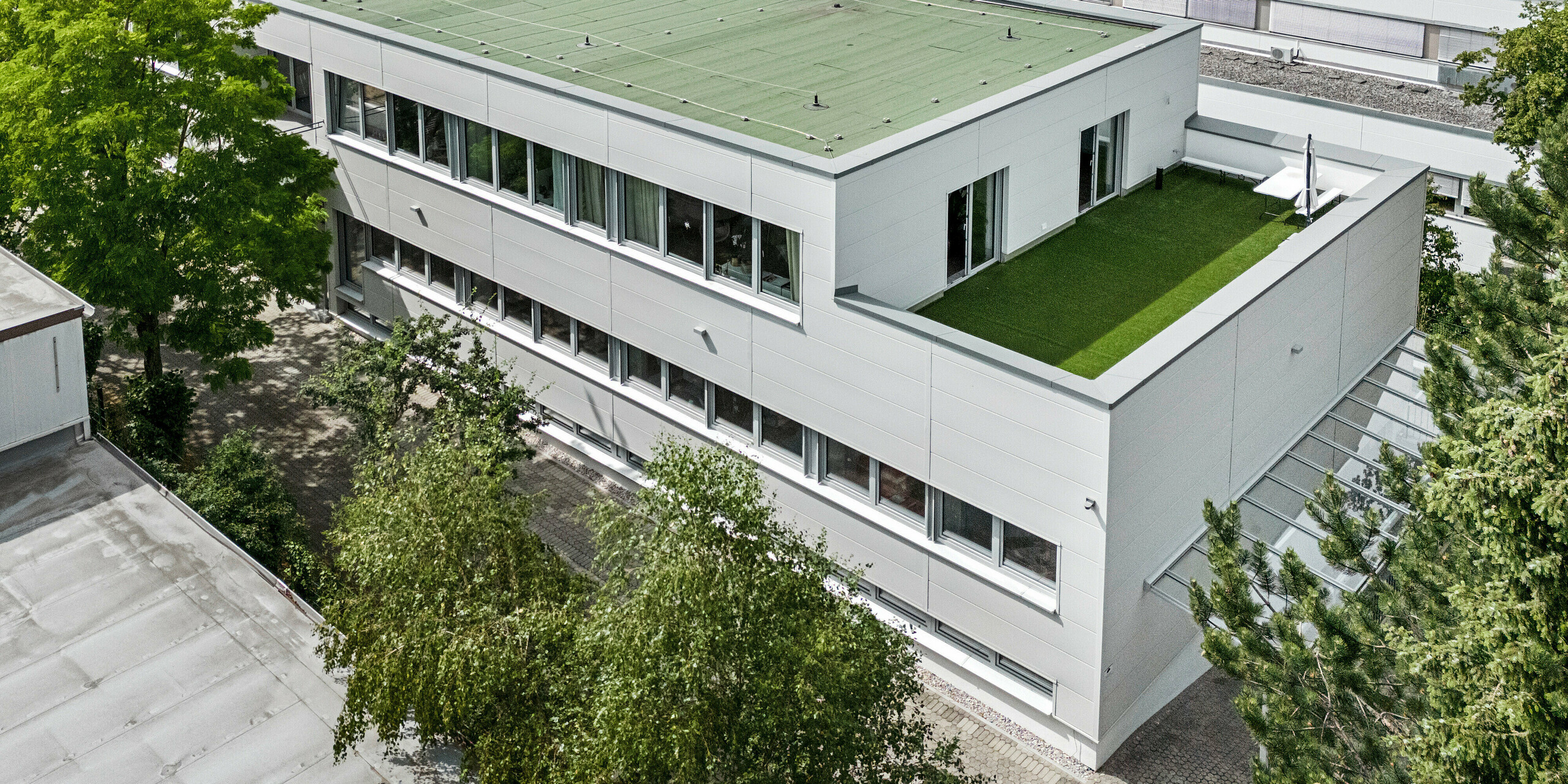Großformatige PREFA Sidings umhüllen ein Firmengebäude in Oberschleißheim (Deutschland). Die extrabreiten Fassadenelemente aus Aluminium sind in der Farbe Prefaweiß gehalten.