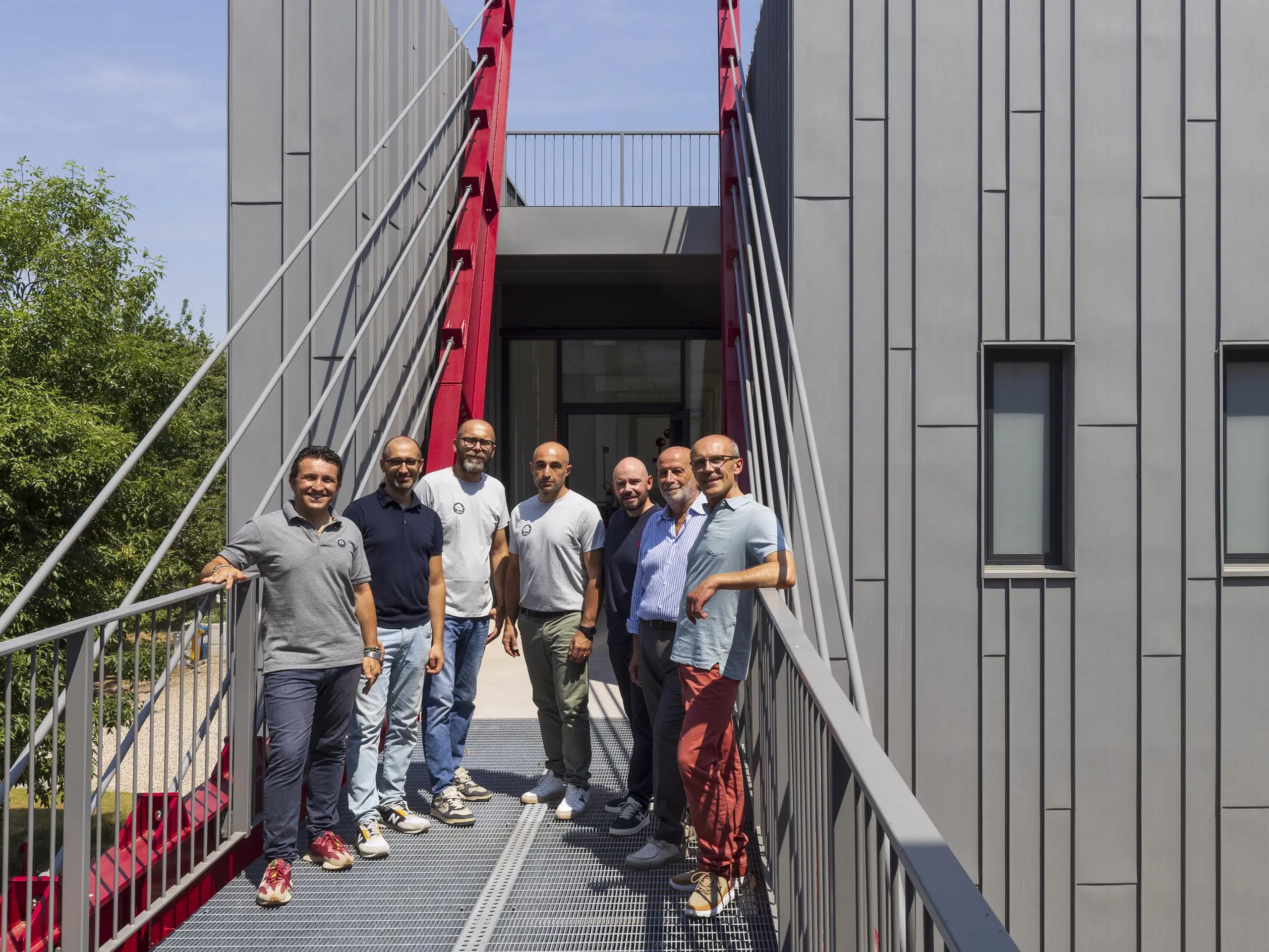 Foto di gruppo di installatore, progettista e consulente PREFA sul pontile di collegamento della scuola Arte e Mestieri di Suzzara.