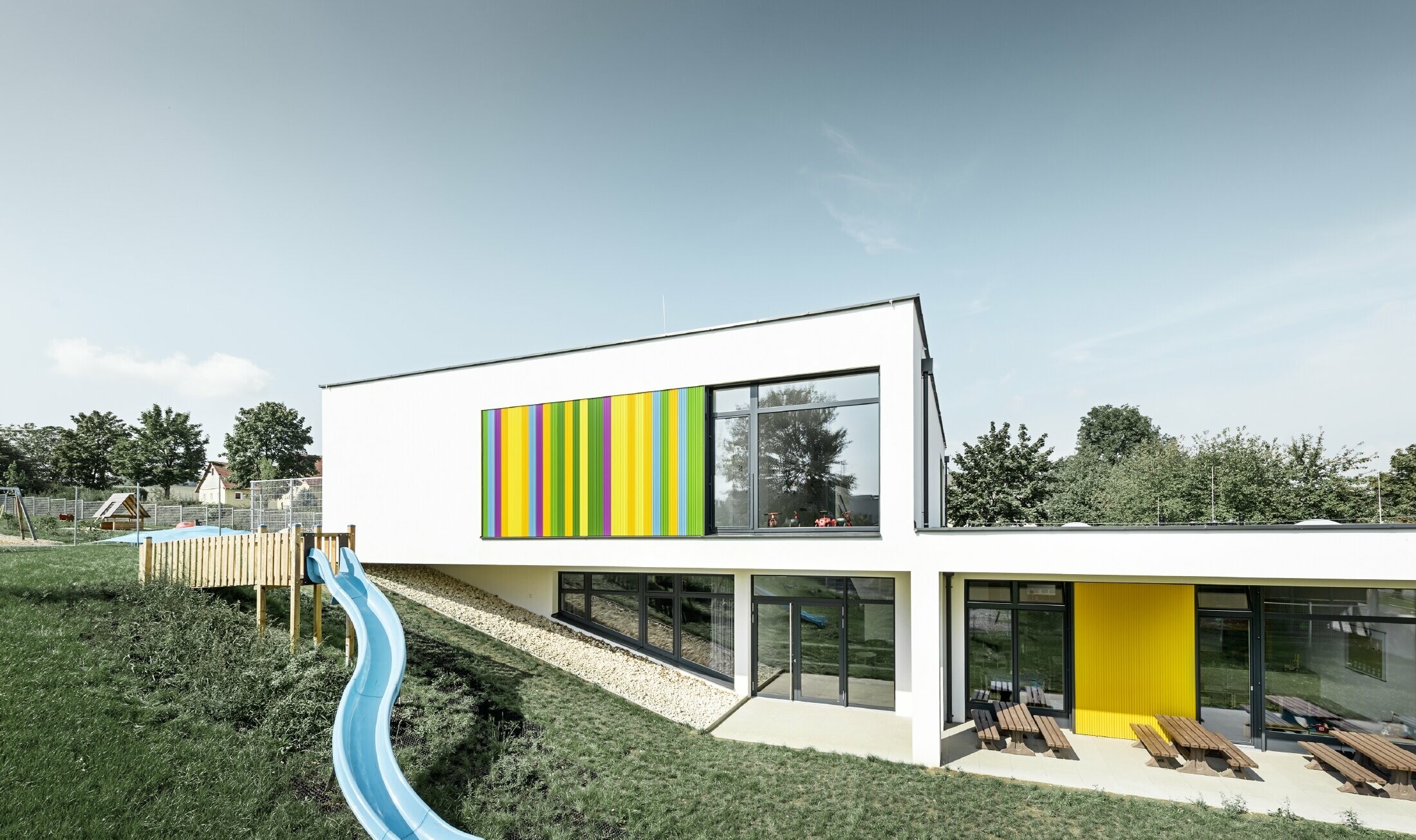 Veduta posteriore della scuola materna ad Hargelsberg con profilo a zeta colorato PREFA in giallo, verde, lilla e blu