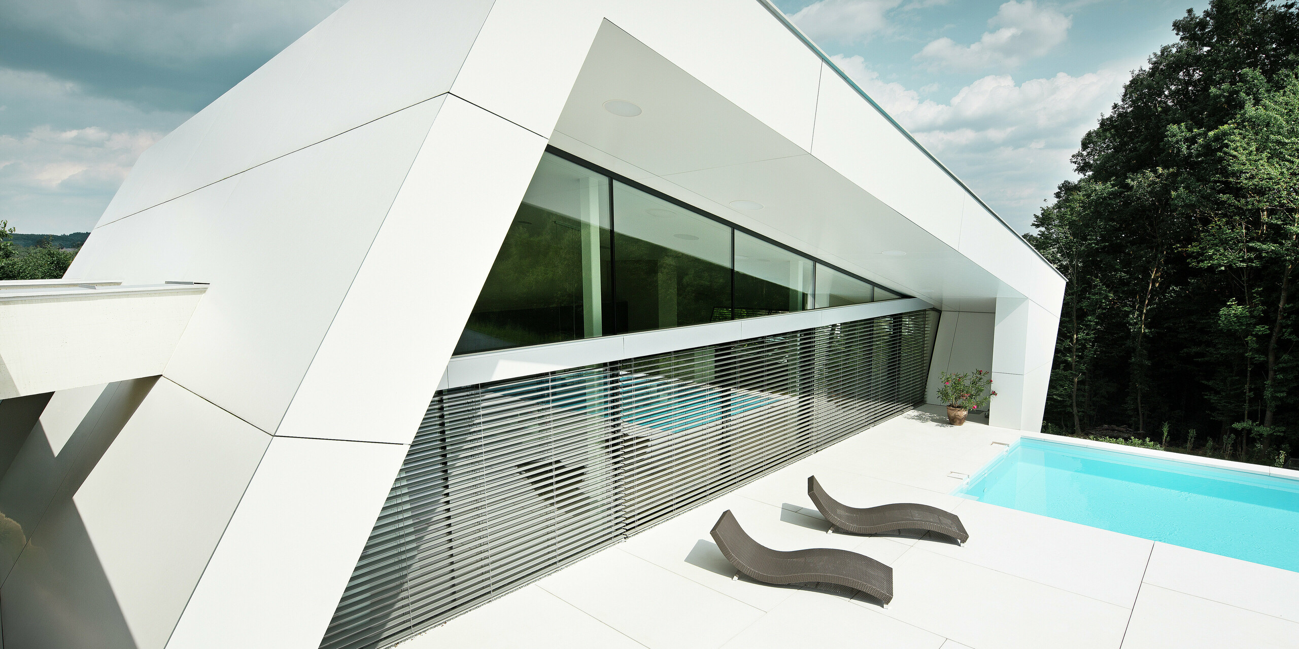 Die elegante Poolterrasse wird von einer geradlinigen PREFA Fassade in P.10 Reinweiß eingefasst. Die Aluminium Verbundplatten sorgen nicht nur für eine moderne Optik, sondern auch für langlebigen Schutz in allen Witterungslagen.