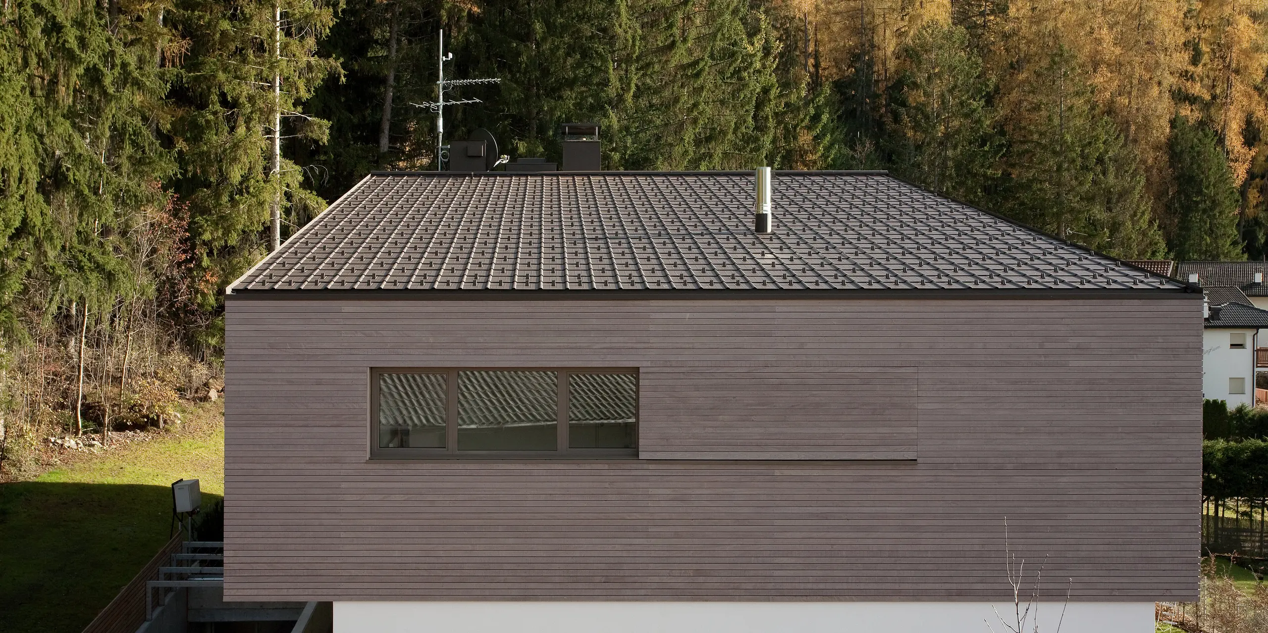 Dachansicht des modernen Gebäudes mit PREFA Dachplatten in P.10 Braun, die sich perfekt in die alpine Landschaft integrieren. Die klare Linienführung des Hauses und das zurückhaltende Design betonen die zeitlose Ästhetik.