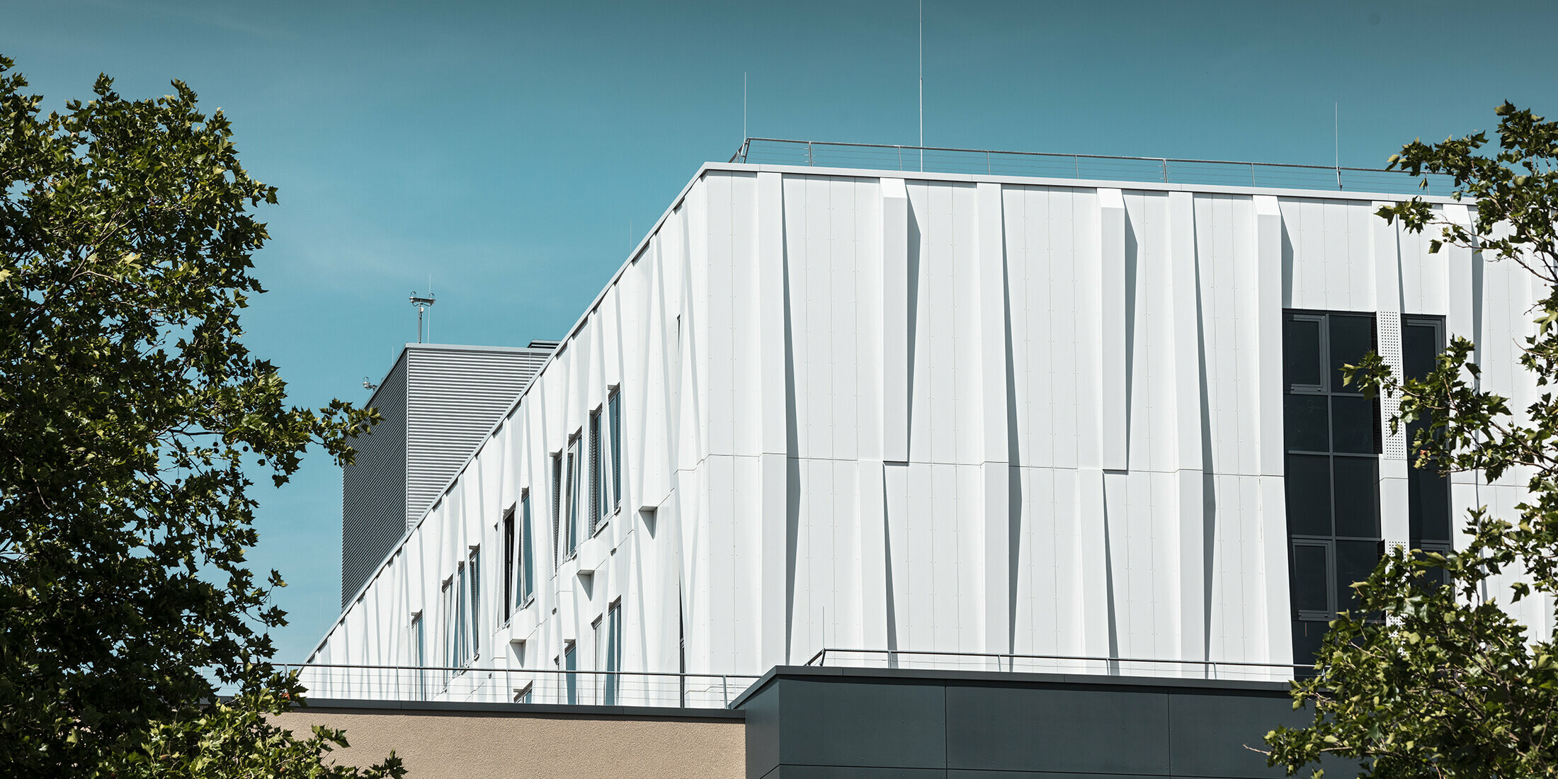 Blick aus der Ferne auf die reinweiße Aluminiumfassade des Universitätsklinikums St. Pölten. Die Aluminiumverbundplatten als Kassettenfassade machen das Gebäude zu einem Blickfang.