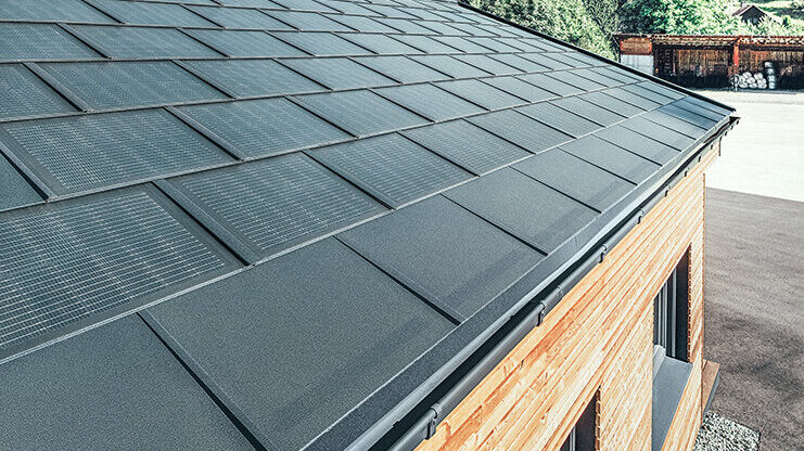 PREFA Solardachplatte in großer Ausführung kombiniert mit der Dachplatte R.16 in Schwarz, Kastenrinne und Lärchenholz-Fassade
