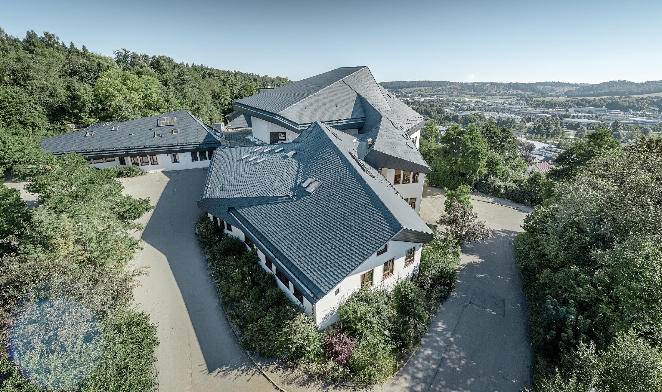 Waldorfschule in Heidenheim mit neu saniertem Dach, die große Dachfläche mit vielen Verwinkelungen und Dachneigungen wurde mit der PREFA Dachschindel in anthrazit eingedeckt