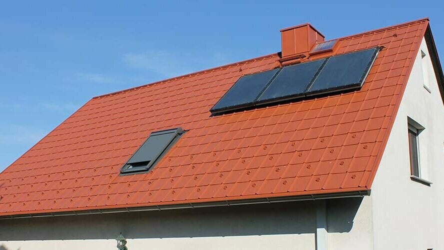 Einfamilienhaus mit Satteldach eingedeckt mit der PREFA Dachplatte in Ziegelrot. Dachfläche inklusive Solaranlage und Dachfenster