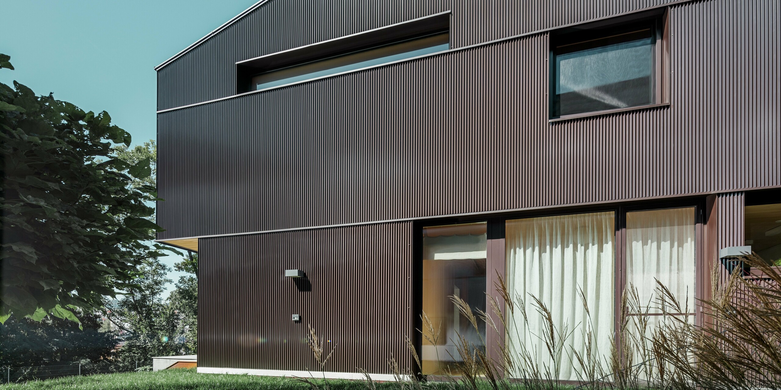 Moderna casa unifamiliare con rivestimento della facciata con profilo a zeta PREFA in marrone.
