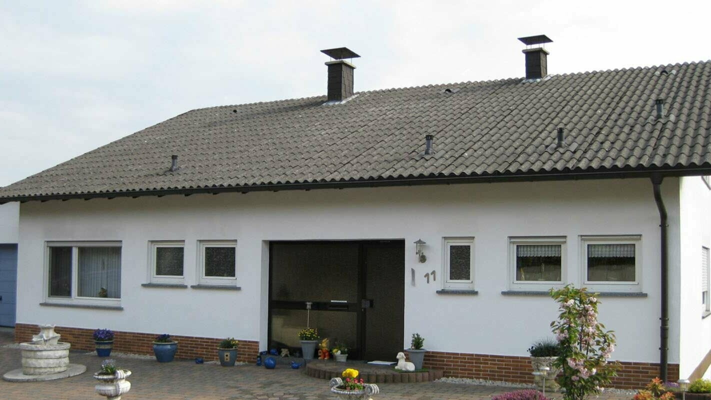Einfamilienhaus mit gewelltem Faserzement vor der Dachsanierung mit der PREFA Dachplatte