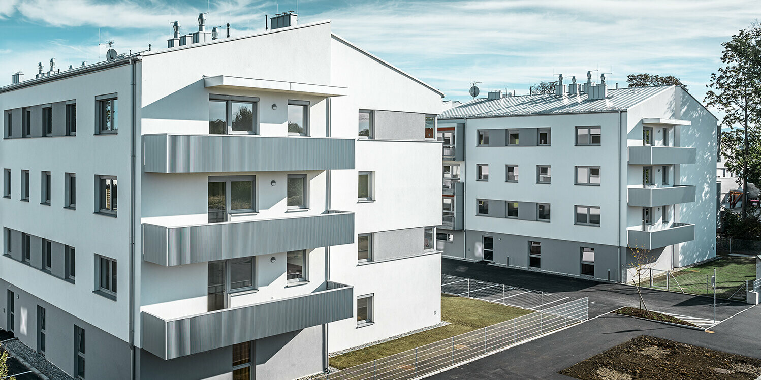 Moderne Wohnhausanlage mit weißer Fassade und Balkonen mit PREFA Zackenprofil in Silbermetallic
