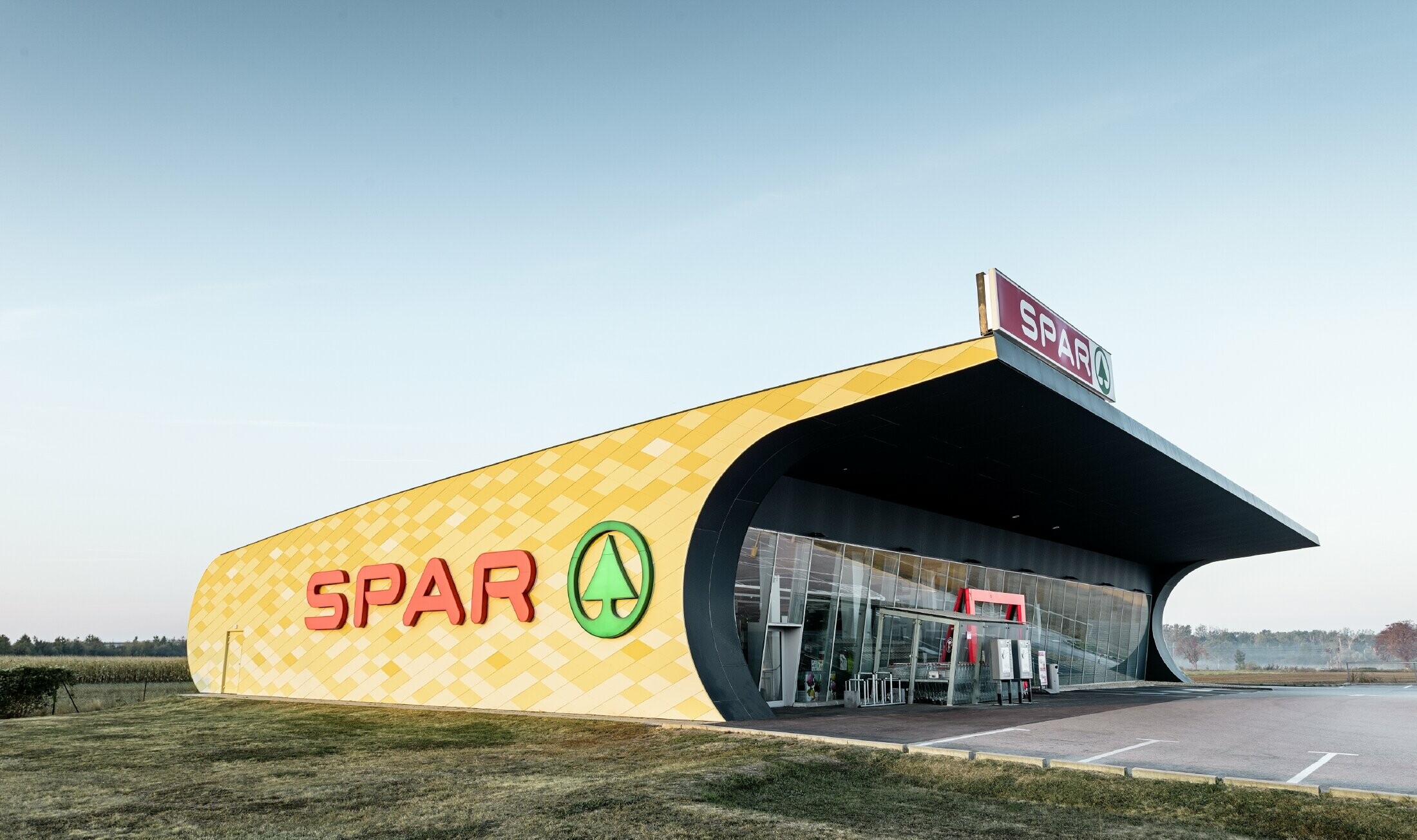 Filiale di Spar con una facciata in alluminio in quadri gialli e arancioni e logo Spar