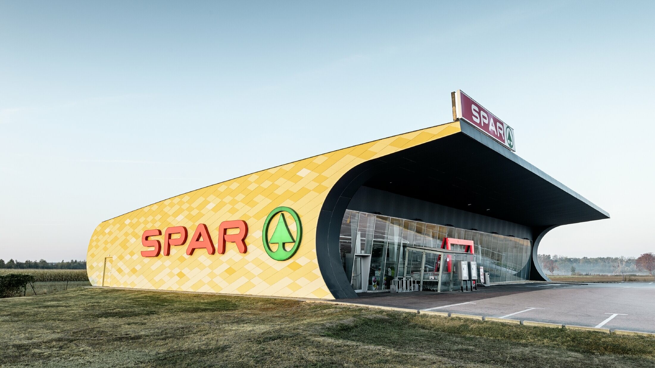 Filiale di Spar con una facciata in alluminio in quadri gialli e arancioni e logo Spar