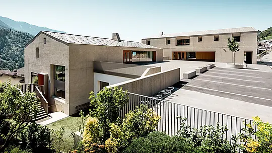 Il centro educativo di Riffian, in Alto Adige, presenta due edifici di grande impatto con scaglie 44 × 44 PREFA nella finitura P.10 bronze, incastonati in uno scenario alpino. La copertura in alluminio, realizzata con precisione, sottolinea le linee pulite, garantisce una protezione duratura e resistente alle intemperie e unisce l’asilo, la scuola elementare e il soleggiato cortile scolastico in un moderno complesso architettonico.
