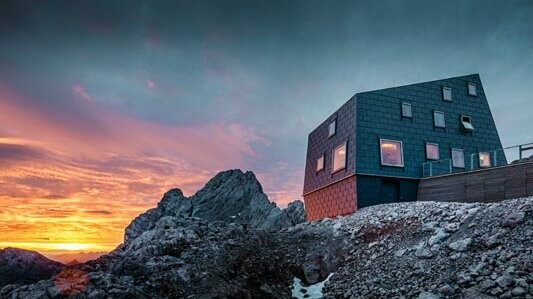 Außergewöhnliche Architektur in den Bergen: die Seethalerhütte am Dachstein eingedeckt mit dem PREFA Dach- sowie Fassadenpaneel Fx.12 in Steingrau.