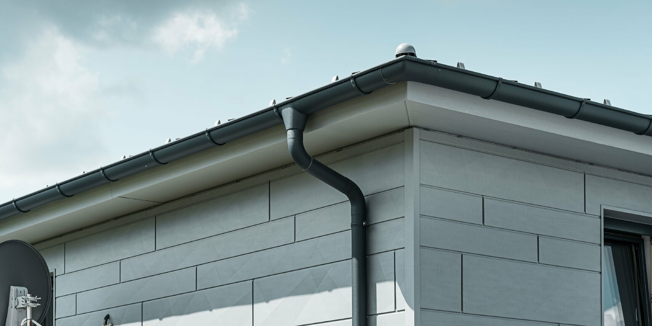 Soffitto con grondaia PREFA, bocchetta e tubo pluviale antracite con facciata in Doga.X PREFA grigio patina