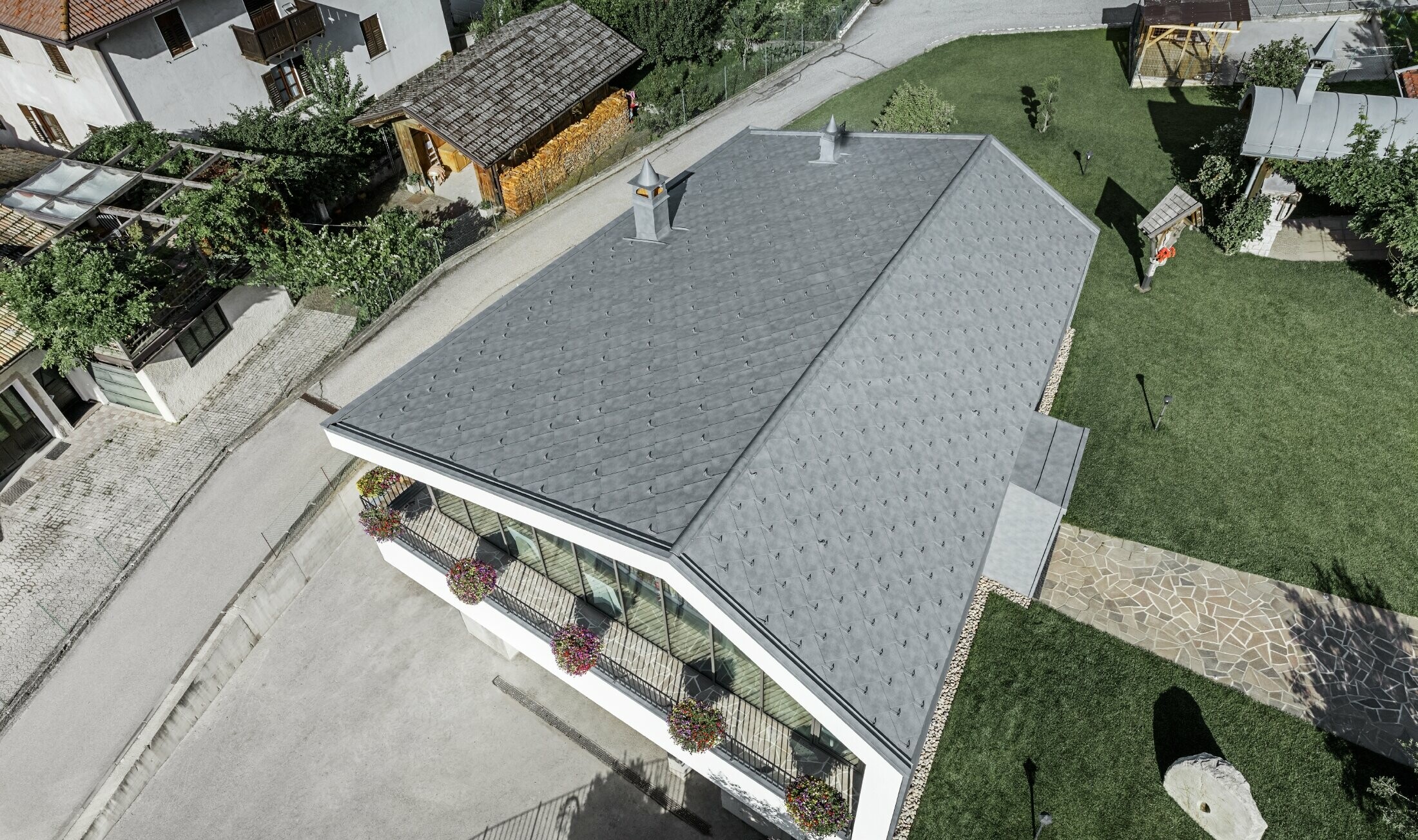 Prospettiva aerea del salone di bellezza a Livo con tetto a due falde rivestito da scaglia in alluminio PREFA in grigio pietra