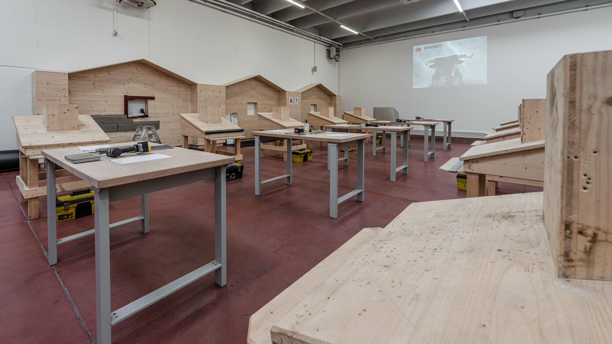 Praxisbereich der PREFA Academy mit Arbeitstischen und Dachobjekten aus Holz.