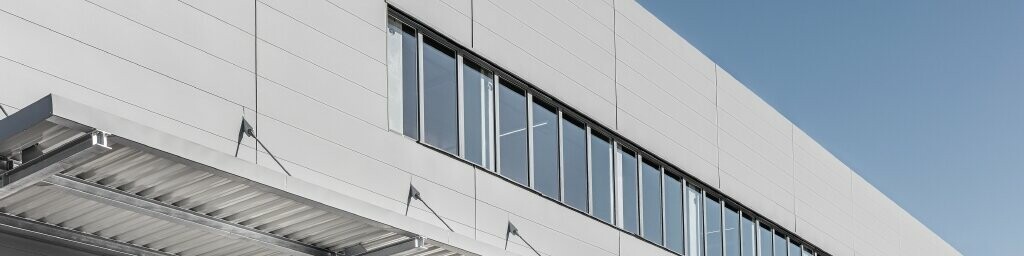 Foto di un edificio rivestito con le doghe PREFA di nuova dimensione. Le larghezze più ampie sono un vantaggio per l'aspetto finale della facciata.