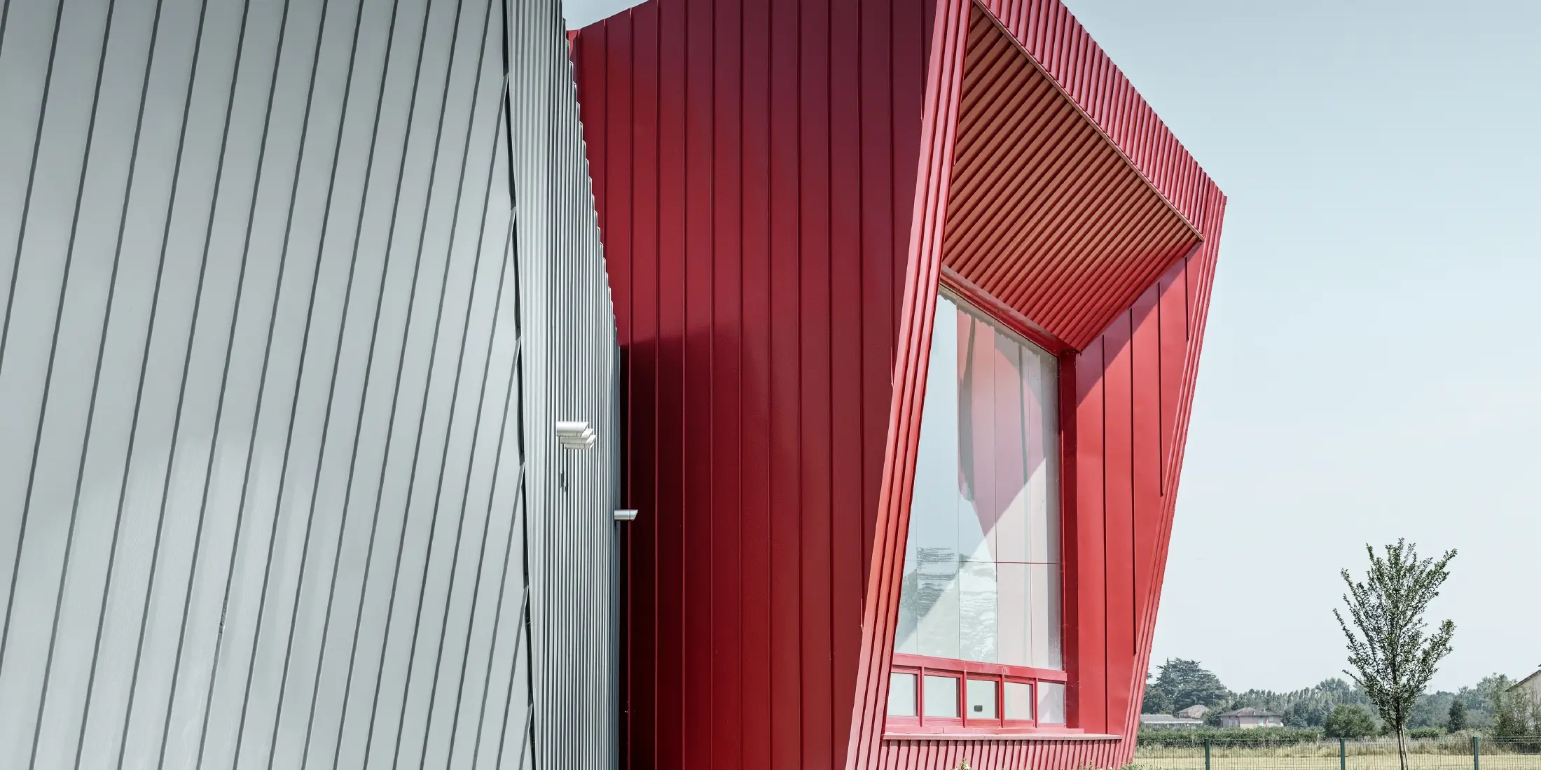 modernes Trainingscenter von Dieci in Montecchio Emilia, Italien, mit Tribüne mit Aluminiumfassade mit Prefalz in hellgrau und Falzonal in karminrot 