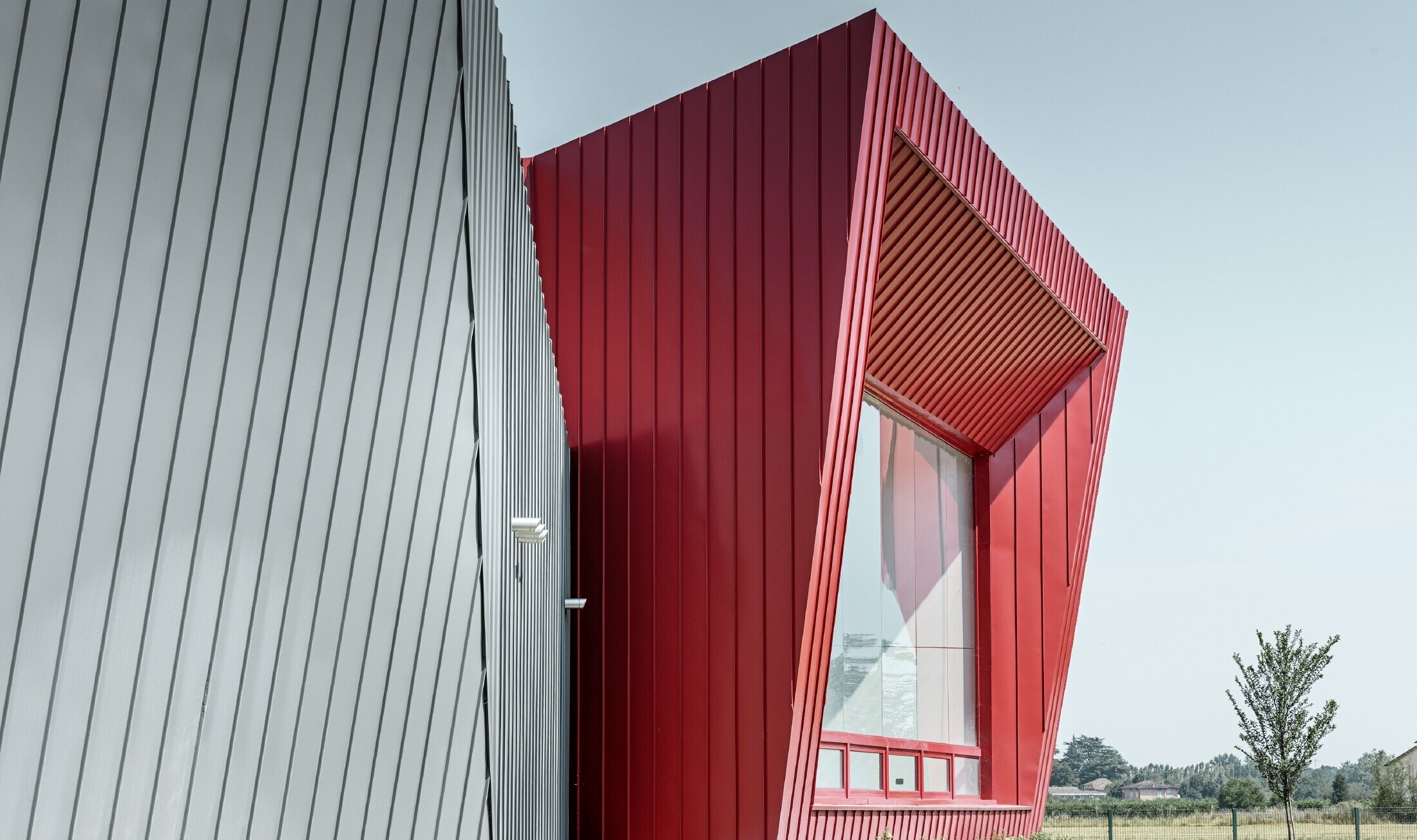 modernes Trainingscenter von Dieci in Montecchio Emilia, Italien, mit Tribüne mit Aluminiumfassade mit Prefalz in hellgrau und Falzonal in karminrot 