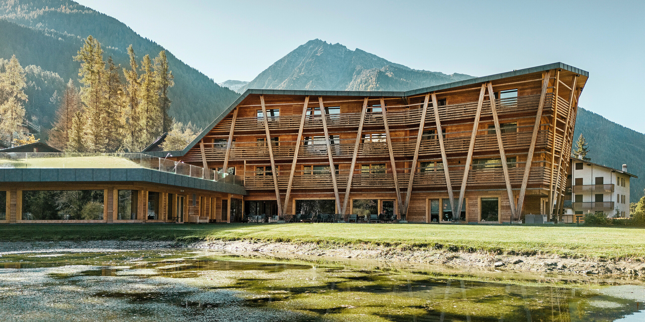 Der kleine See vor dem Luxus-Öko-Hotel Au Charmant Petit Lac in Champluc mit einem PREFALZ-Dach in P.10 Steingrau und einer Holzfassade..