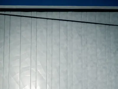 Zwei ArchitektInnen begutachten die PREFA Siding.X Fassade die in durch die Sonneneinstrahlung in verschiedenen Spiegelungen erscheint