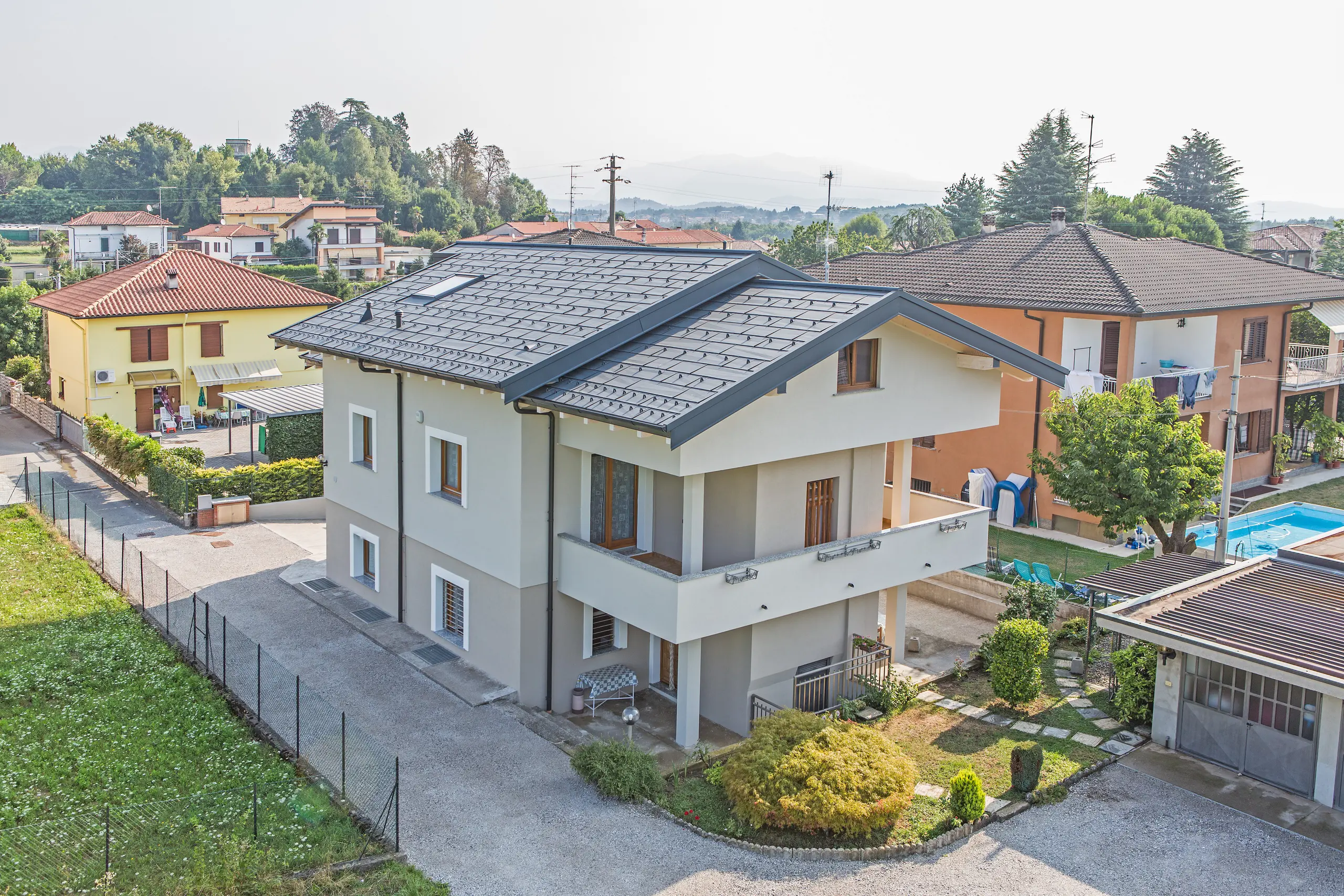 Modernes Einfamilienhaus in Beregazzo, Italien, mit markantem Satteldach aus PREFA Dachpaneelen FX.12 in P.10 Anthrazit. Die unregelmäßig gekanteten Aluminium-Paneele erzeugen ein lebendiges Licht- und Schattenspiel und setzen einen starken architektonischen Akzent. Das langlebige PREFA Aluminiumdach verbindet zeitgemäßes Design mit hoher Widerstandsfähigkeit und zuverlässigem Schutz vor Witterungseinflüssen.