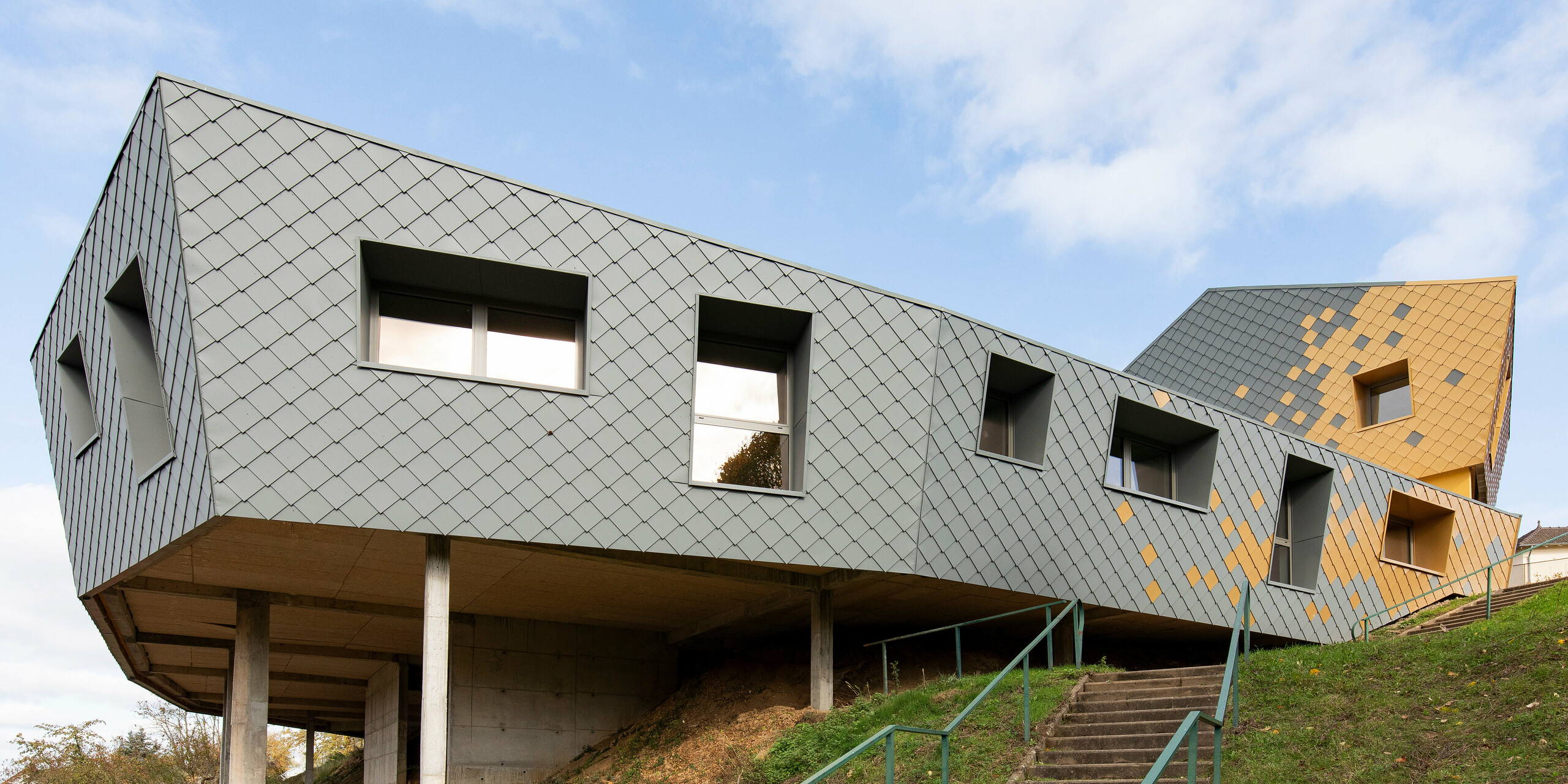 Grundschule Jean Peyraud in Pierre-Buffière in Hanglage mit Fassade aus PREFA Wandrauten 29 × 29 in P.10 Hellgrau und Mayagold