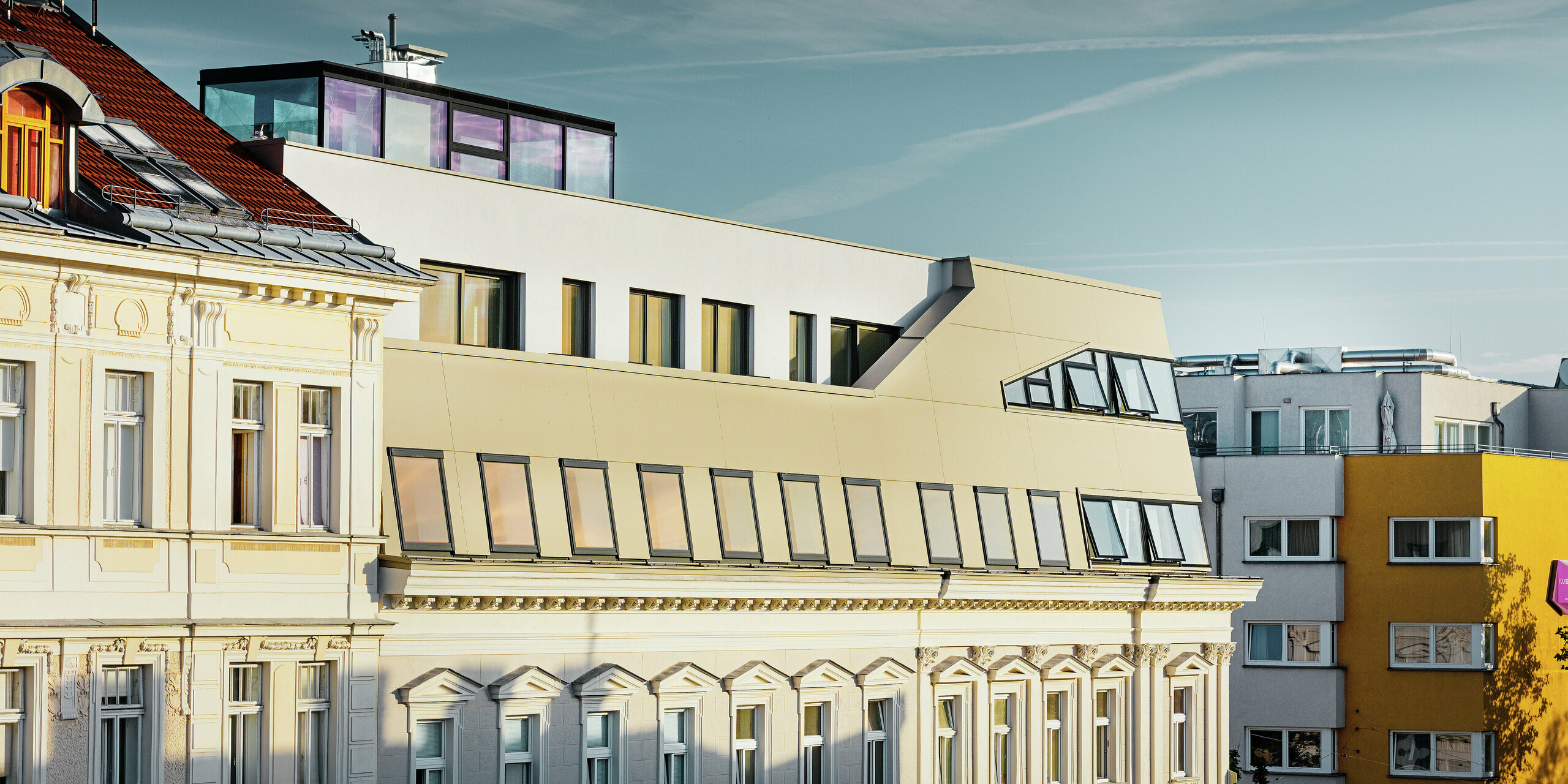 Die Fassade des ausgebauten Dachgeschosses kontrastiert stilvoll mit der ornamentreichen Gründerzeitfassade. Die edle PREFA Aluminiumverkleidung in Bronze sorgt für ein hochwertiges, wetterbeständiges und modernes Erscheinungsbild mitten in der Wiener Innenstadt.