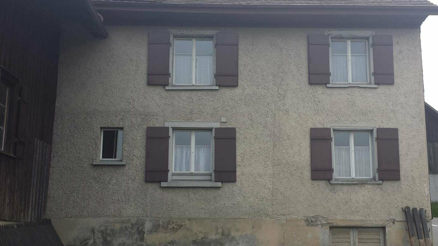 Casa prima della ristrutturazione della facciata con losanghe PREFA, finestre con persiane rosse