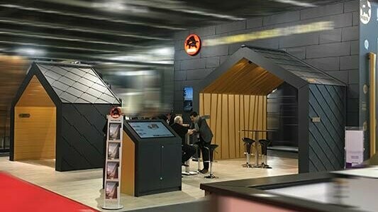 PREFA Messestand mit Messewänden in P.10 schwarzen Siding.X und Rauten und Falzonal in Savannenbeige.