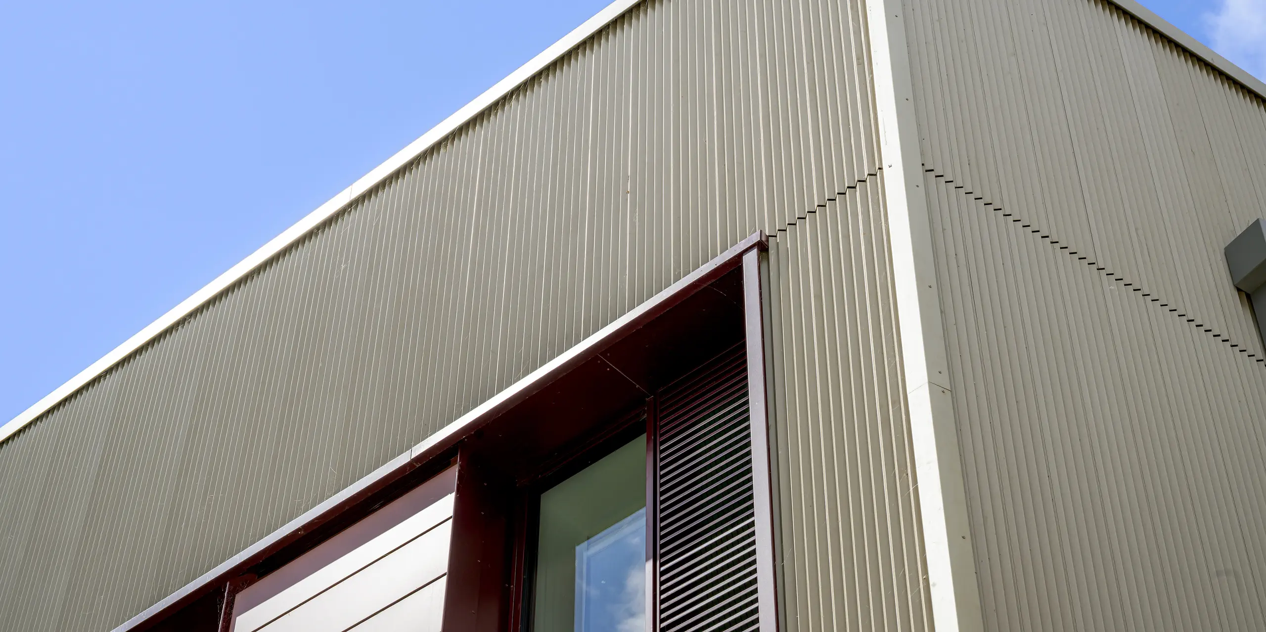 Die Detailaufnahme der Currie Community High School in Edinburgh rückt die PREFA Fassade mit Strangpressprofil Zacke in den Fokus. Die filigrane, vertikale Aluminiumstruktur in P.10 Prefabronze erzeugt ein faszinierendes Spiel aus Licht und Schatten und betont die klare Gebäudekante. Das hochwertige PREFA Aluminium überzeugt dabei durch Langlebigkeit, Korrosionsbeständigkeit und eine dauerhaft elegante, wartungsarme Fassadengestaltung.