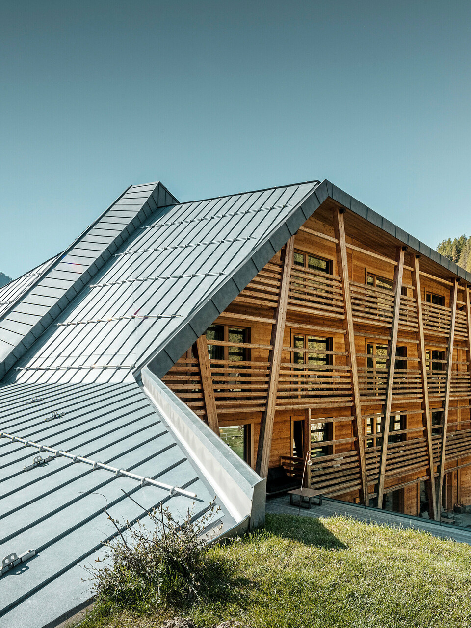Das Hotel 'Au Charmant Petit Lac' in Champoluc zeigt eine einzigartige architektonische Harmonie, bei der das PREFALZ Dachsystem in P.10 Steingrau gekonnt mit der holzverkleideten Struktur des Gebäudes verschmilzt. Die dynamische Dachgestaltung mit ihren klaren Linien und Falzen fügt sich nahtlos in die umliegende Alpenlandschaft ein und bietet einen modernen Kontrast zur traditionellen Holzbauweise. Diese Kombination aus modernen und natürlichen Materialien spiegelt das Engagement des Hotels für umweltbewusstes Design und Nachhaltigkeit wider.