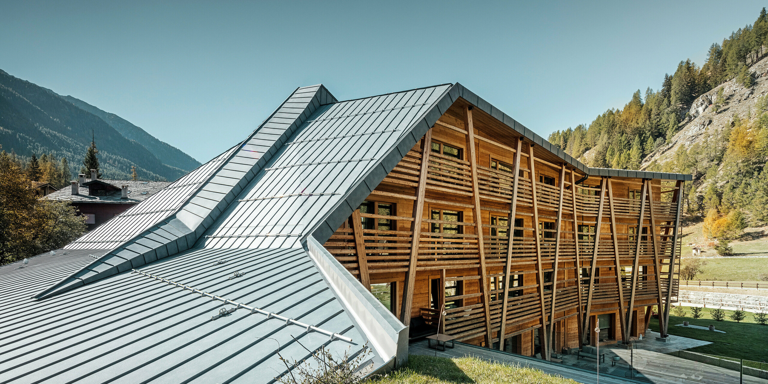 Luxus-Öko-Hotel Au Charmant Petit Lac in Champluc mit einem PREFALZ-Dach in P.10 Steingrau und einer Holzfassade.
