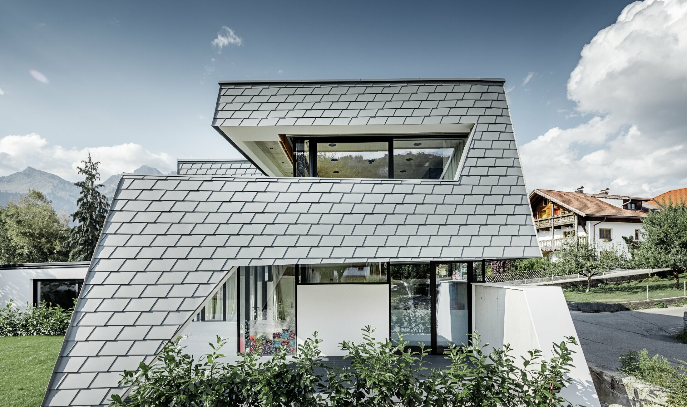 casa unifamiliare moderna con copertura piana, ampie superfici vetrate e una facciata in scandola in grigio chiaro in alluminio PREFA
