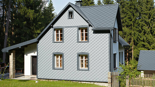 Casa monofamiliare con sistema completo PREFA; la facciata è rivestita con losanghe 29 PREFA color grigio chiaro.