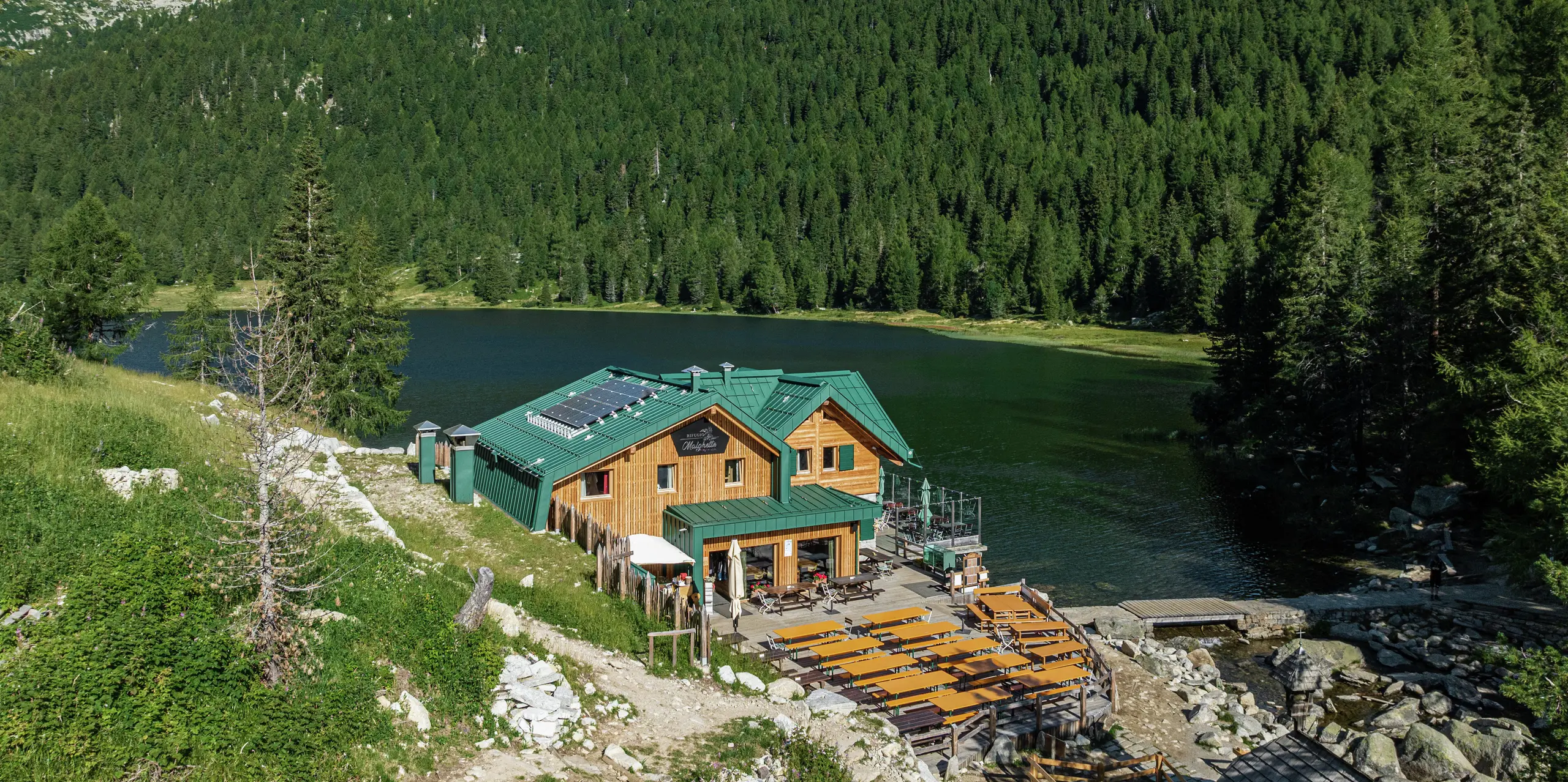 Das Rifugio Malghette auf 1.888 m, idyllisch am See gelegen, mit dem PREFALZ Dach in P.10 Moosgrün - wetterfest, langlebig und perfekt in die Natur integriert. Die großzügige Sonnenterrasse lädt Wanderer zum Verweilen ein, das widerstandsfähige Aluminiumdach trotzt selbst extremem Bergwetter.