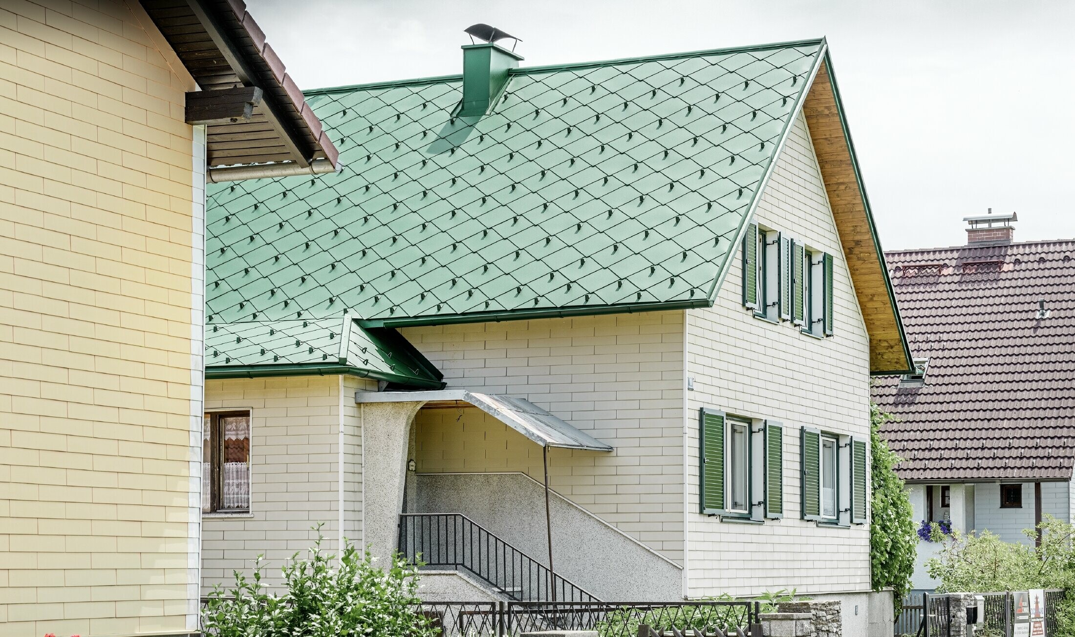 Casa unifamiliare classica con tetto a doppia falda con una copertura in alluminio in verde muschio con scuri verdi.