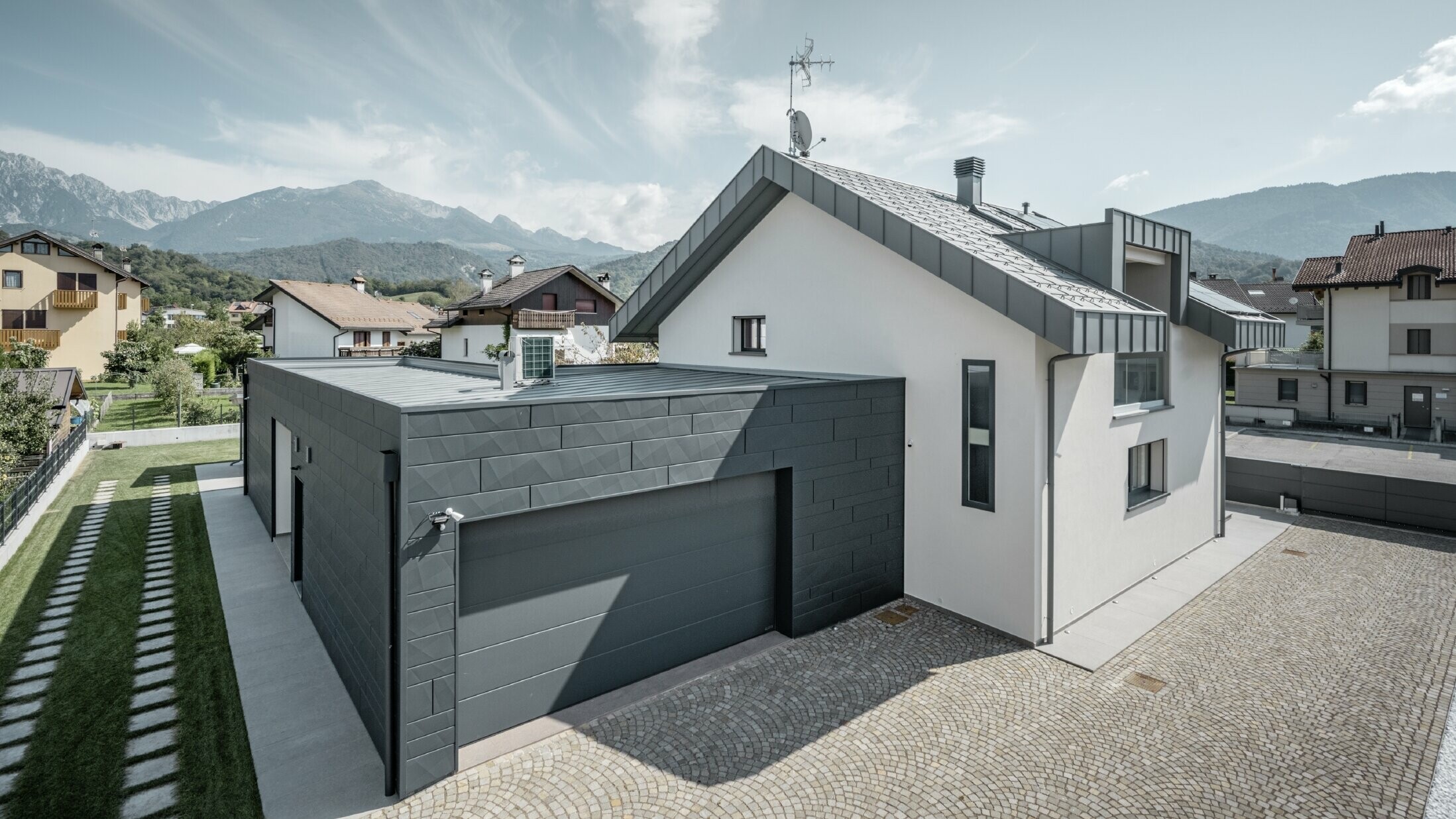 Foto vom Einfamilienhaus, die Garage ist mit Siding.X gedeckt, das Dach ist in R.16 in der Farbe P.10 hellgrau gedeckt.
