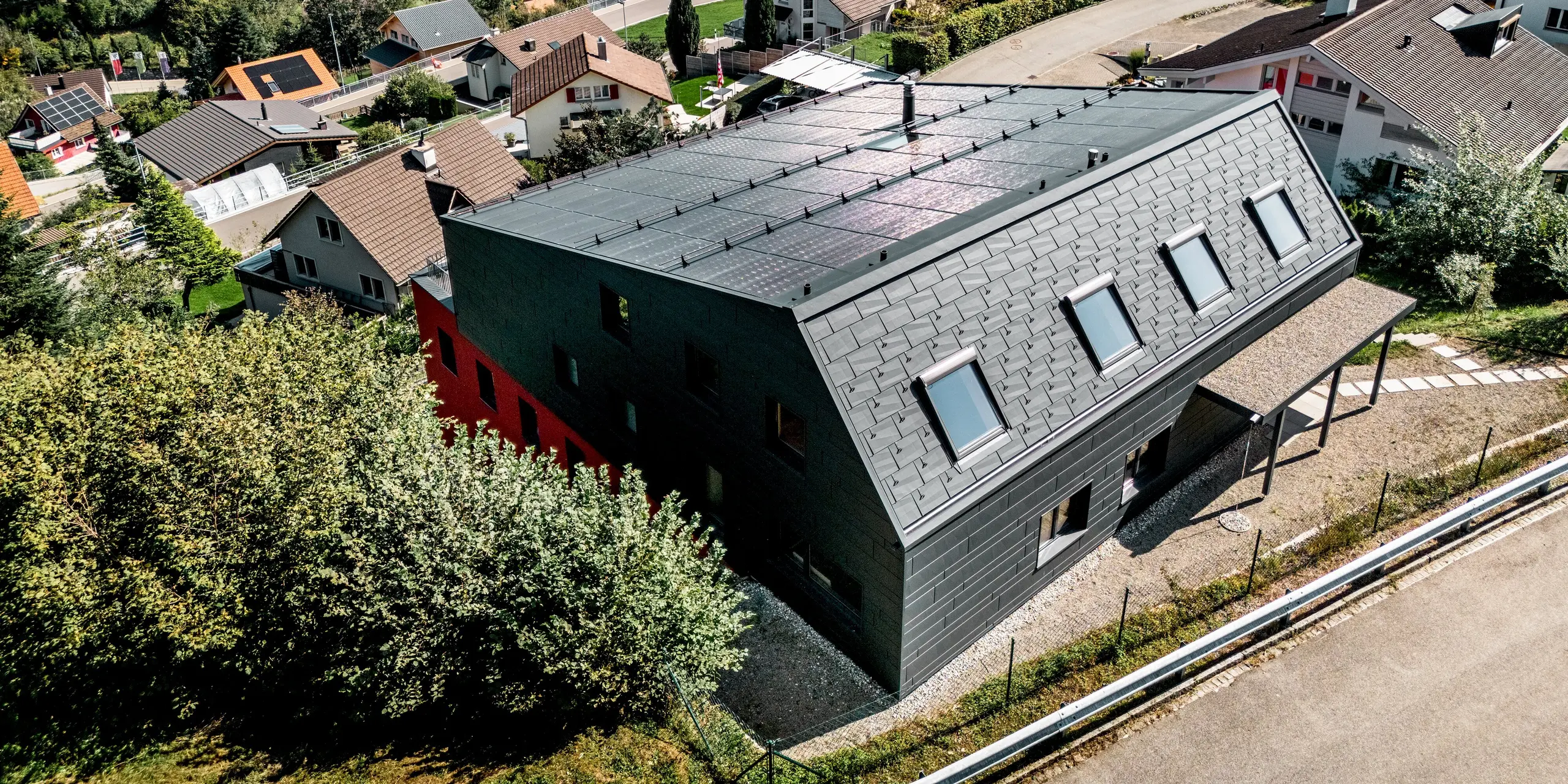 Aus der Vogelperspektive zeigt sich das Weinwerk Wienacht-Tobel eindrucksvoll in der Hügellandschaft über dem Bodensee. Das PREFA Dachpaneel FX.12 und die Siding.X Fassade in P.10 Anthrazit verleihen dem Gebäude eine markante, monolithische Optik. Die langlebigen Aluminiumprodukte überzeugen durch geringes Gewicht, hohe Witterungsbeständigkeit und eine zeitlos moderne Architektur.