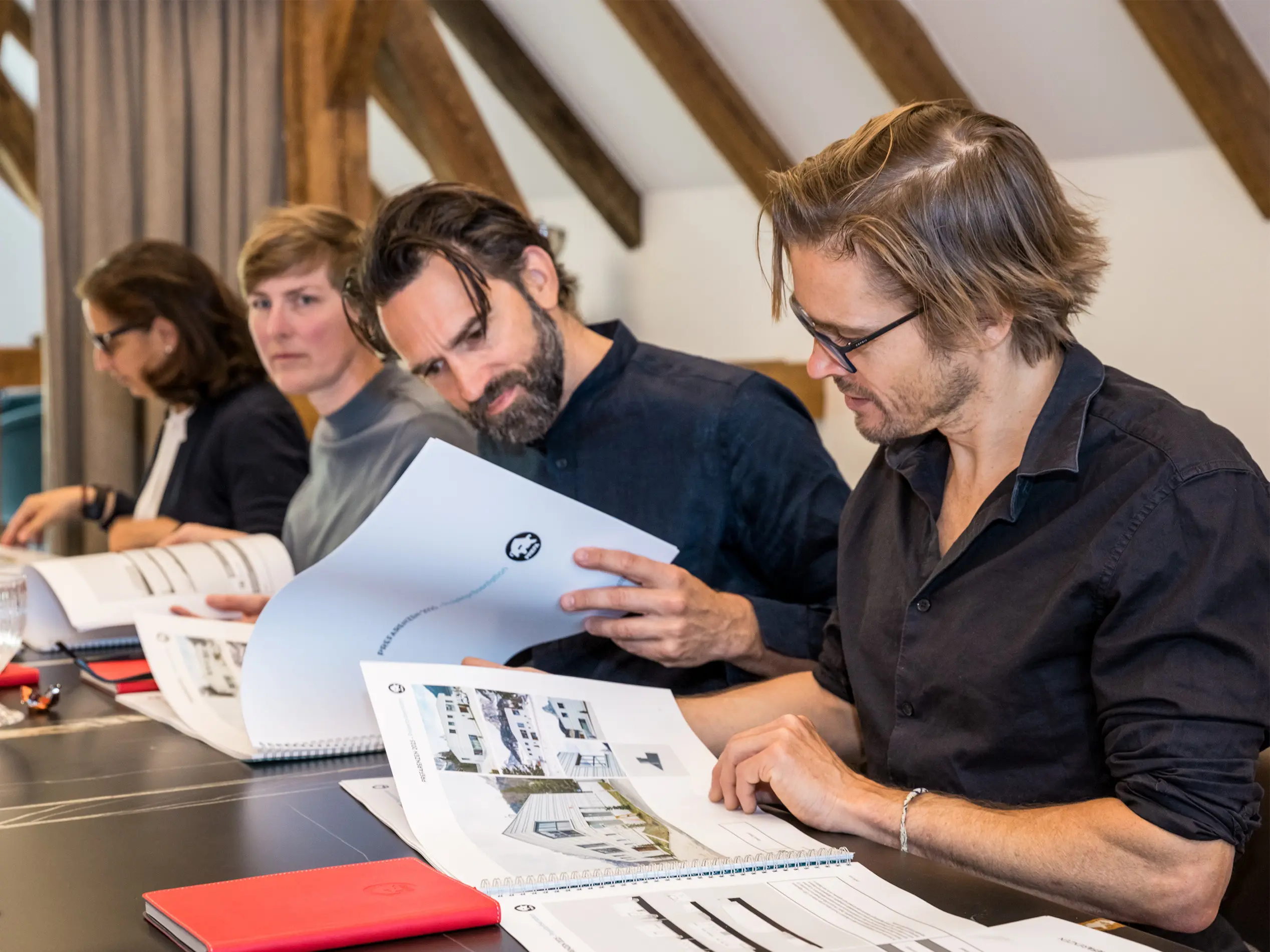 Una giuria di architetti durante la revisione della documentazione per la selezione delle PREFARENZE 2025. I membri della giuria sono seduti a un tavolo e stanno esaminando presentazioni dettagliate dei progetti.
