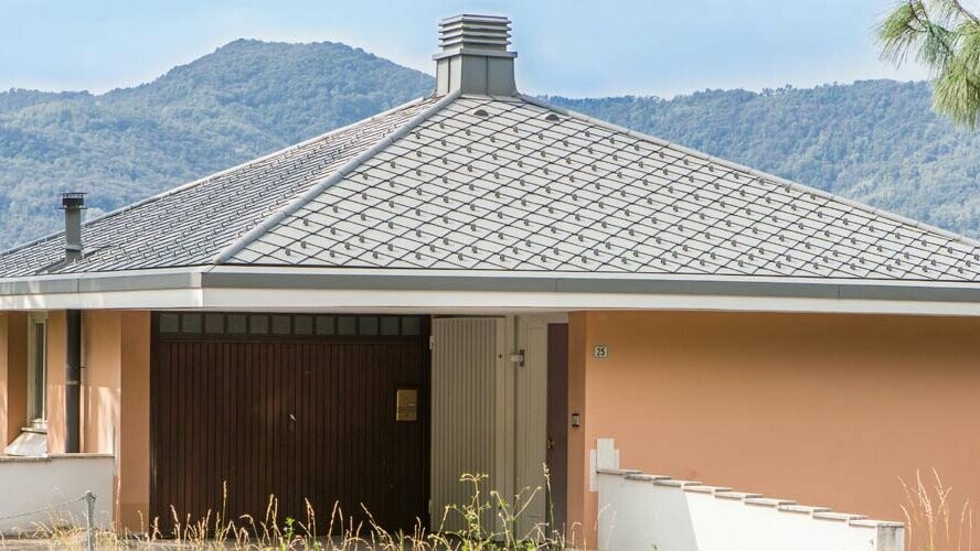 Casa privata di colore arancione con tetto a ombrello, rivestito con scaglie a rombo 29 x 29 PREFA nel colore P.10 grigio chiaro.
