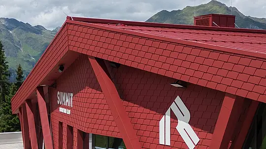 Facciata principale e entrata del Summit Moutain Club a Racines, rivestita in scandole PREFA e vetro.