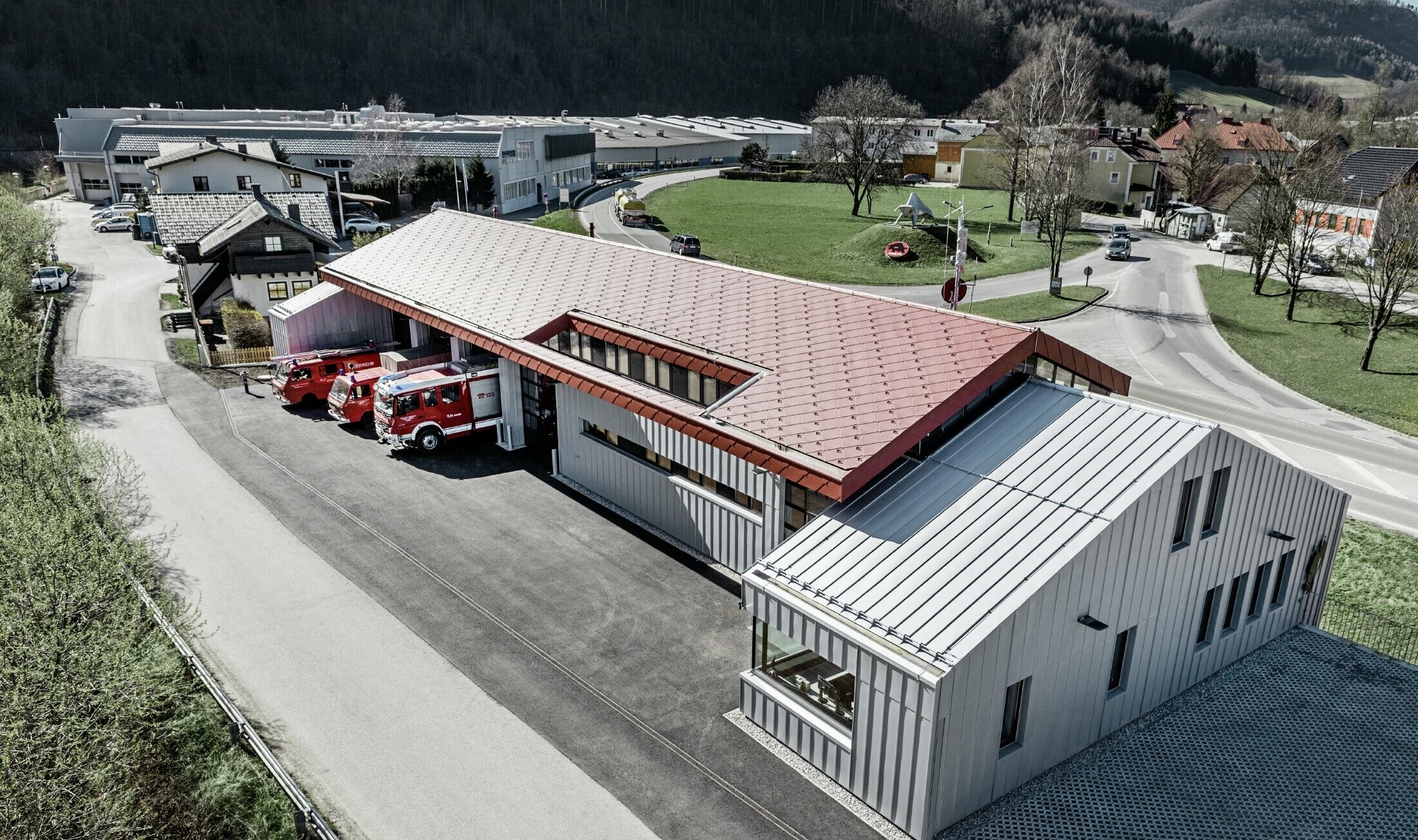 Immagine aerea dei vigili del fuoco aziendali a Marktl/Lilienfeld. La parte sinistra dell'edificio è stata completamente rivestita sul tetto e sulla facciata con la scaglia 44 in rosso ossido. La parte destra ha una copertura in alluminio con Prefalz in silver metallizzato.