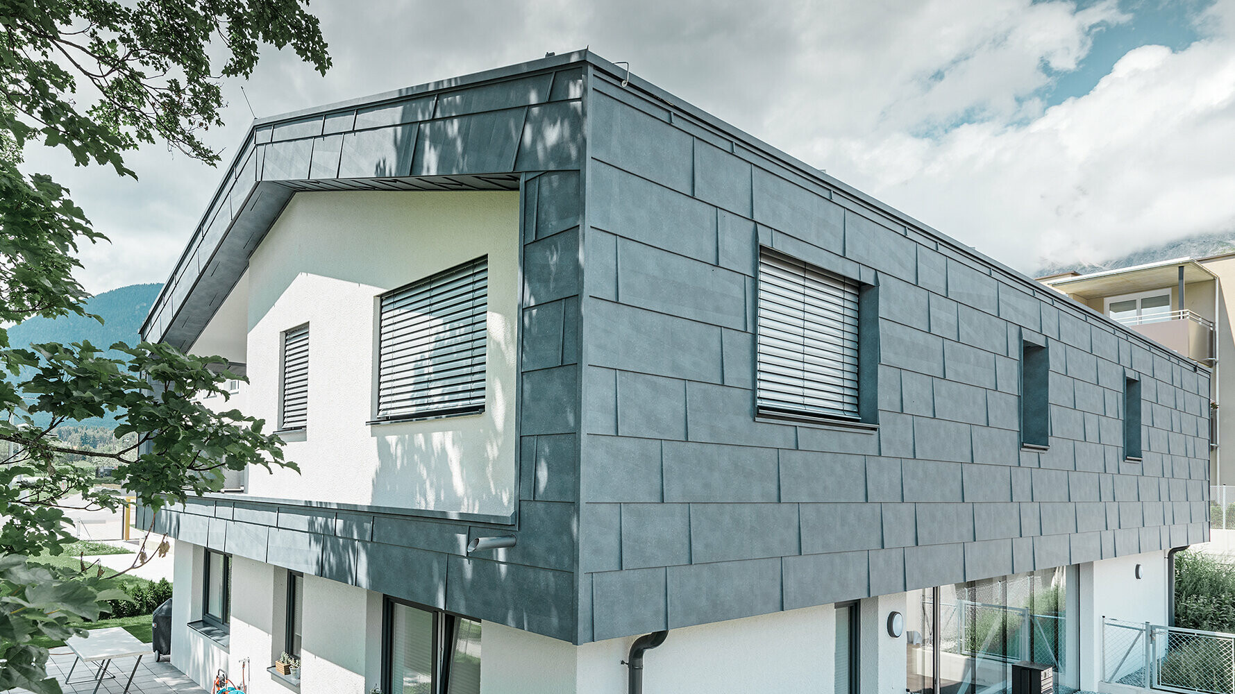 Moderna casa unifamiliare senza centina; il piano superiore è stato rivestito con i pannelli per facciate FX.12 in grigio pietra, il resto della facciata è stato intonacato di bianco.