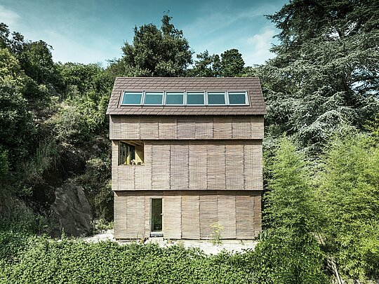 Architettura moderna in Francia - casa con tetto in scandole PREFA in P.10 testa di moro e facciata in salice, situata in posizione ripida su una collina con generosi lucernari.